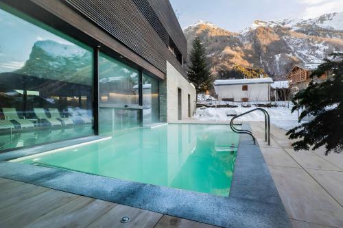 una piscina frente a un edificio con montañas en NH Collection Alagna Mirtillo Rosso, en Alagna Valsesia