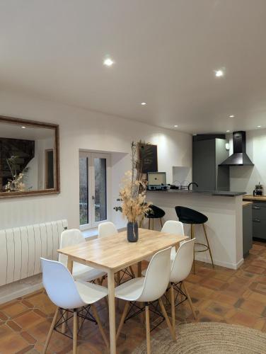 une cuisine et une salle à manger avec une table et des chaises en bois dans l'établissement Maison de campagne au bord du ruisseau-5mn mer, à Lamballe Armor