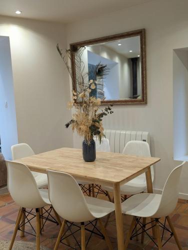 - une table à manger avec des chaises blanches et un miroir dans l'établissement Maison de campagne au bord du ruisseau-5mn mer, à Lamballe Armor