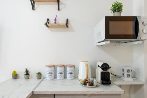 Il comprend une cuisine avec un comptoir, un four micro-ondes et une télévision. dans l'établissement Best Deal! Modern studio in vibrant area only 5 minutes by walk to metro - central location, à Paris