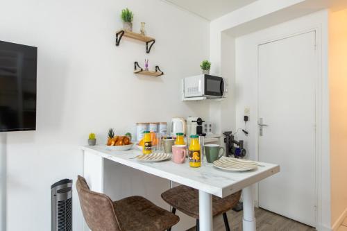 une cuisine avec une table blanche et deux chaises dans l'établissement Best Deal! Modern studio in vibrant area only 5 minutes by walk to metro - central location, à Paris