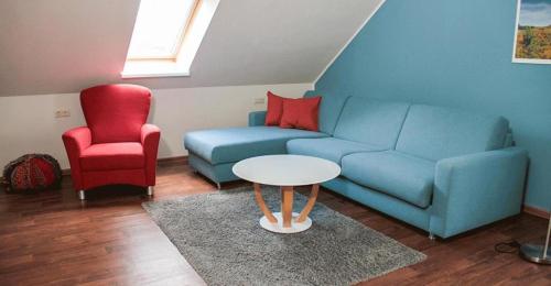 a living room with a blue couch and a red chair at Ferienwohnungen Hafendorf Müritz in Rechlin