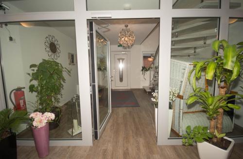 a hallway with potted plants and a glass door at Hotel Sonne am Meer in Norddeich