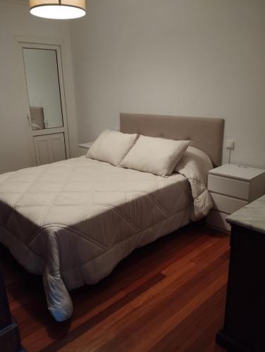 a bedroom with a large bed with white sheets at Mirador urbano sobre el rio in Noya