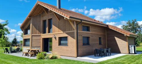 a large wooden house with a table and chairs at CHALET L'ÉCHAPPÉE NATURE 4 étoiles sauna in Anould