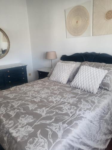 a bed with a gray and white comforter and pillows at Mirador urbano sobre el rio in Noya