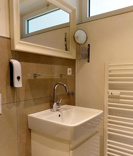 a bathroom with a white sink and a mirror at Apartment Regina am schönen Möhnesee in Möhnesee