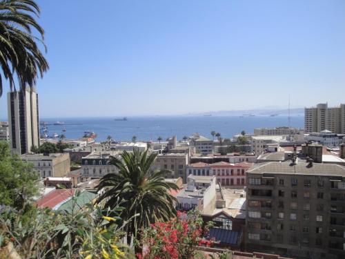 a city with buildings and the ocean in the background at The Travelling Chile in Valparaíso