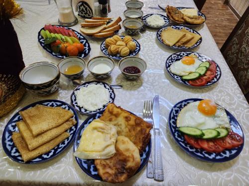 ein Tisch mit Tellern voller Frühstücksspeisen darauf in der Unterkunft Samani Bukhara in Buxoro