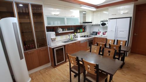 a kitchen with a table and chairs and a refrigerator at Bong Stay in Jeju