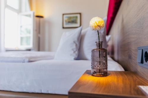 a vase with a flower on a table in a bedroom at Hotel zur Fürstabtei in Herford