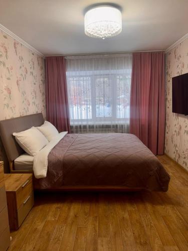 a bedroom with a large bed and a window at Apartment on Bukhar Zhyrau in Karagandy