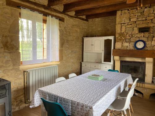 une cuisine avec une table et des chaises ainsi qu'une cheminée dans l'établissement Gite en pierres à la campagne, à Tamniès