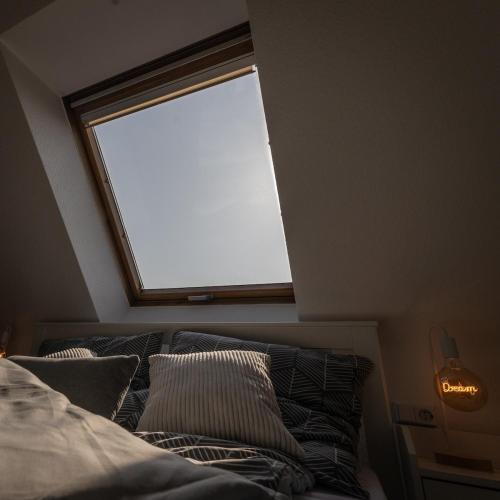 a bedroom with a window and a bed with pillows at Lake Breeze Maisonette bei Leipzig in Markkleeberg