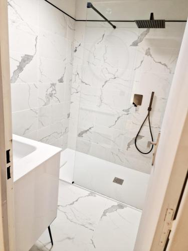 La salle de bains est pourvue de murs en marbre blanc et d'une douche. dans l'établissement Magnifique vue mer - Piscine -Tennis, à Nice