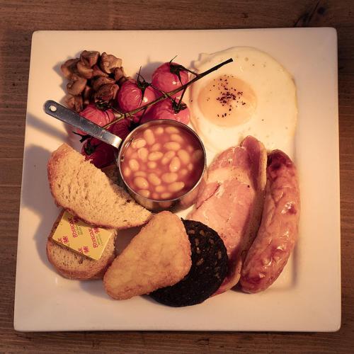 a plate of breakfast food with eggs beans and bread at B&B Glamping Bell Tents at The Ring Pub in Gwredog