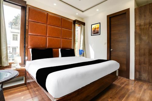a bedroom with a large bed with a wooden headboard at Super Collection O Mall Road Nainital in Nainital