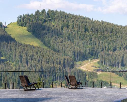 two chairs sitting on a balcony with a mountain at Hotel Podgorie Spa in Bukovel