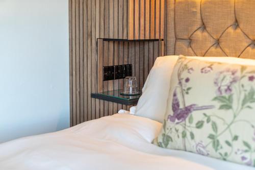 a close up of a bed with a pillow and a night stand at Holly Lodge Guest House with FREE off site health club in Windermere
