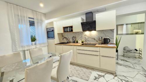 a kitchen with white cabinets and white chairs at ISTRIANA by Istrian apartments Koper in Koper