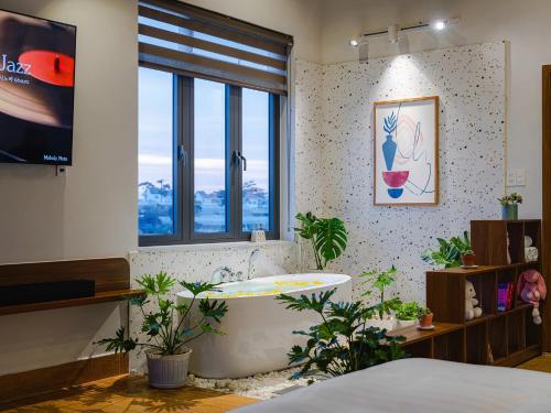 a bathroom with a tub and a window and plants at Teen Hillside Đà Lạt- View Nhà Lồng lãng mạn in Da Lat