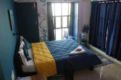 a bedroom with a blue and yellow bed and a window at Uday's Sea Green in Pallipuram