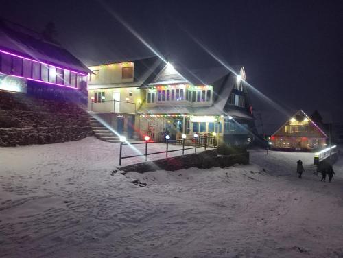 a building in the snow at night with lights at kalingchwok hotel tik top in Dolakhā