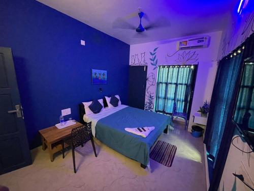 a blue bedroom with a bed and a table at Uday's Sea Green in Pallipuram