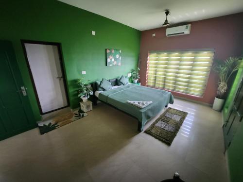a bedroom with a bed and a green wall at Uday's Sea Green in Pallipuram