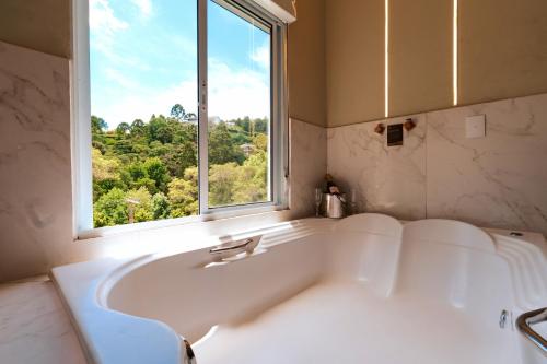 a white bath tub in a bathroom with a window at Pousada Recanto dos Sonhos in Campos do Jordão
