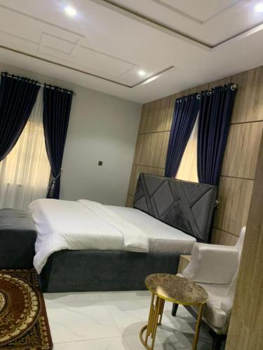 a bedroom with a bed and a chair and windows at Chexfield Hotels and Apartments 2427 in Abuja