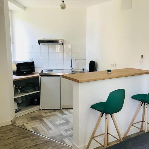 une cuisine avec un comptoir et deux tabourets de bar verts dans l'établissement Appart - central - Cœur historique, à Sarlat-la-Canéda