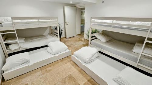 Cette chambre comprend 3 lits superposés avec des oreillers blancs. dans l'établissement Appartement provençal 10 personnes, au Castellet