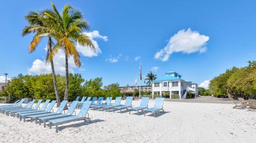 a row of chairs on a beach with palm trees at Ocean View Treehouse Double King Suite 3403 in Tavernier