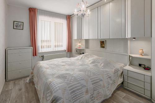 a bedroom with a bed and white cabinets and a chandelier at Stephanie 0406 G30 in Sint-Idesbald