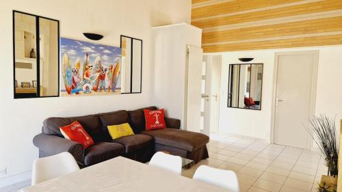 ein Wohnzimmer mit Sofa und Tisch in der Unterkunft Le Rivage, maison proche mer avec Spa in Les Sables-dʼOlonne