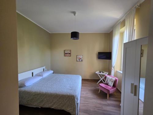 a bedroom with a bed and a pink chair at Casa Fraeli in Pozzuoli
