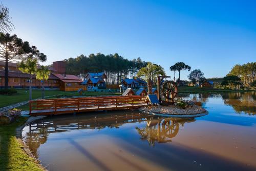 a pond with a wooden bridge in a park at Hospedaria Morada das Grimpas in Palmeira