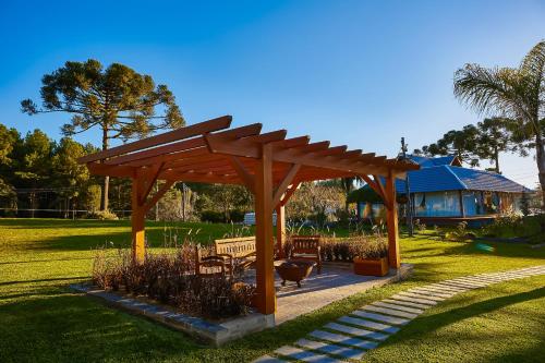 a wooden pergola in a park with a house at Hospedaria Morada das Grimpas in Palmeira