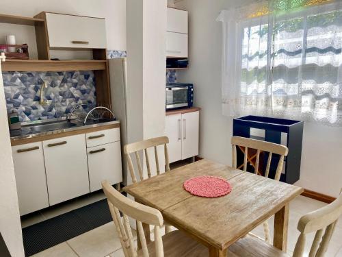 a small kitchen with a wooden table and chairs at Red House - Casa com Linda vista do Mar in Palhoça