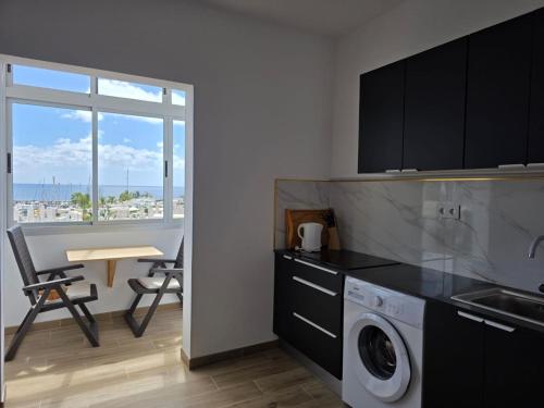 a kitchen with a washing machine and a table and a window at Casa Balcon 2 bedroom by El Sirocco in Puerto de Mogán