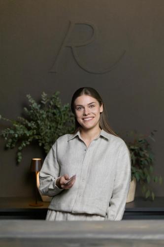 a woman is standing next to a table at Hotel Reja, a Member of Design Hotels in Klaipėda