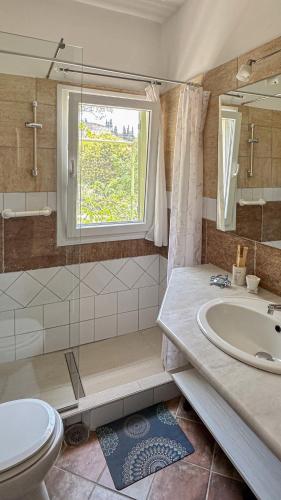 a bathroom with a sink and a toilet and a window at Mouse House in Gouvia