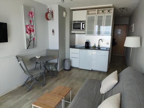 Il comprend une petite cuisine et un salon avec un canapé et une table. dans l'établissement Résidence TROUVILLE, à Châtelaillon-Plage