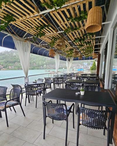 a restaurant with tables and chairs and a view of the water at Hotel Royal Drina in Mali Zvornik
