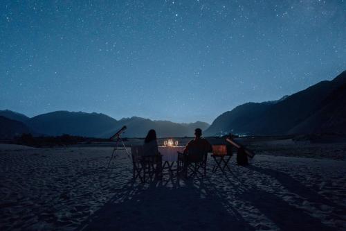 a group of people sitting around a table at night at Stone Hedge Hotel in Nubra