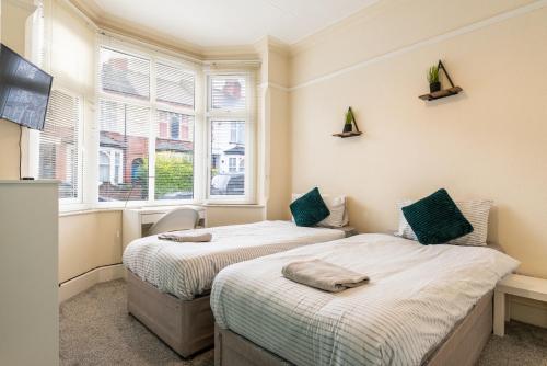 two beds in a room with two windows at Beacon House in Leicester