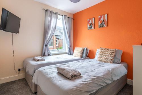 two beds in a room with an orange wall at Beacon House in Leicester