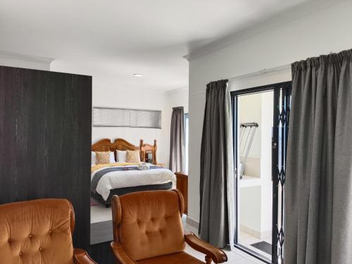 una camera da letto con un letto e due sedie di Large Suite - Dream Den at Rustic Dune 3 a Jeffreys Bay