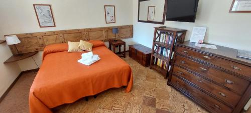 a bedroom with a bed with an orange blanket and a dresser at Oryza Guest House in Desana